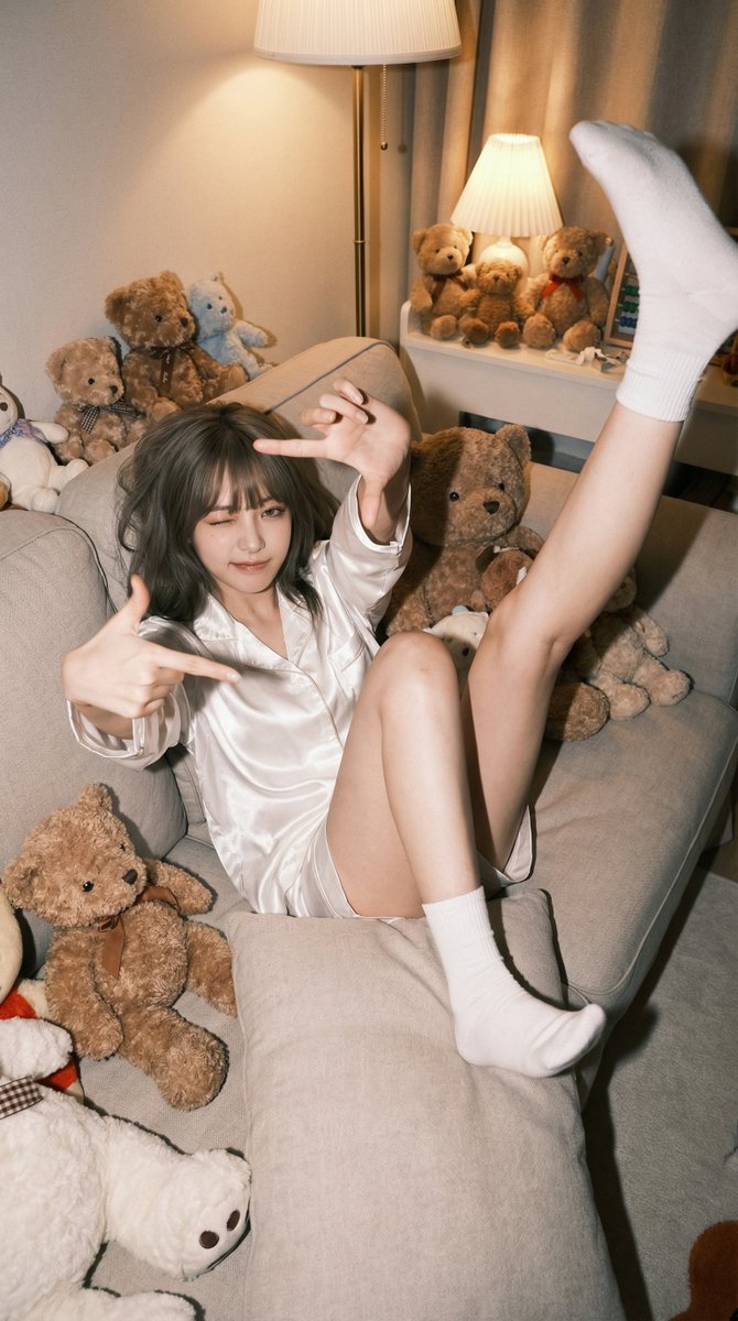 一个放松的年轻女性,穿着舒适的白色缎面睡衣,在可爱的卧室沙发上摆出活泼的姿势